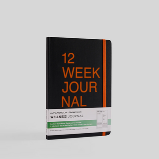 A black notebook with '12 Week Journal' written on the cover in orange text. It has rounded corners and an elastic closure.