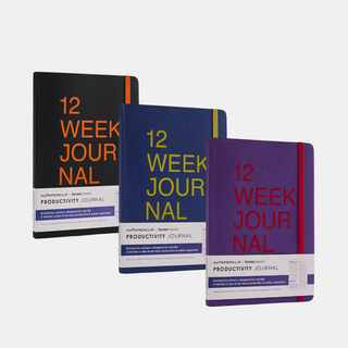 Three books in black, blue, and purple with '12 Week Journal' written on the cover. All have rounded corners and an elastic closure.
